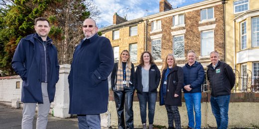 Representatives from Zenith Mechanical Services, Prosper, Tyne Housing, Keelman Homes, North Star Housing, Livin Housing, and Durham Aged Mineworkers’ Homes smiling outside a terraced property