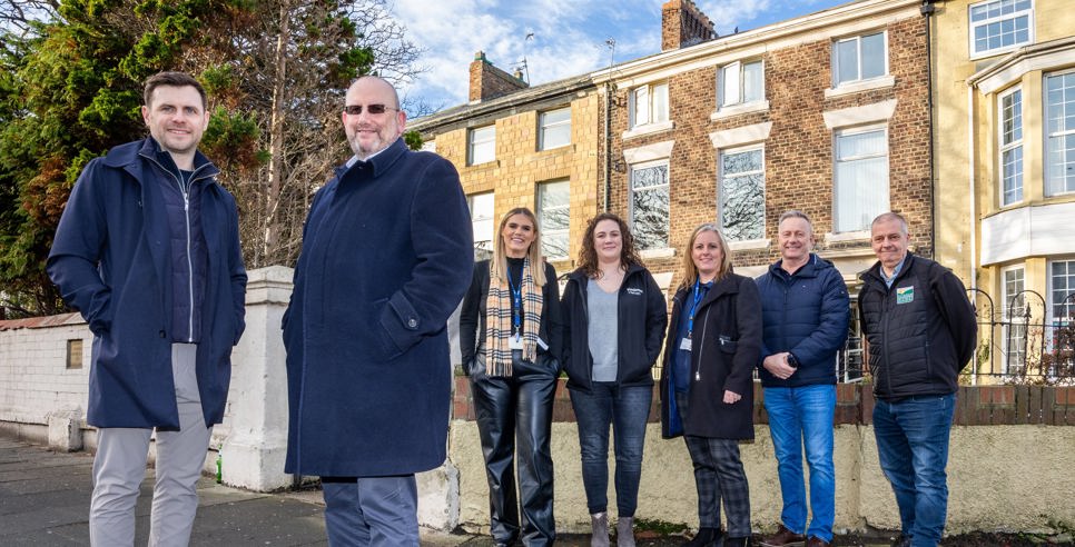 Representatives from Zenith Mechanical Services, Prosper, Tyne Housing, Keelman Homes, North Star Housing, Livin Housing, and Durham Aged Mineworkers’ Homes smiling outside a terraced property